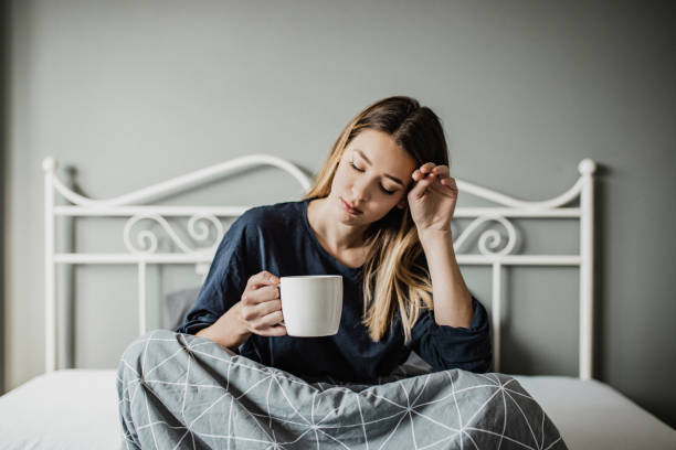 istock Sad young tired woman sitting on the bed 1276512876