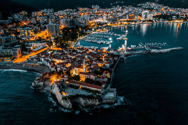 Budva at night with all the city lights adn reflections in the sea The beauty of Budva at night with all the city lights and reflections in the water of the Adriatic sea seen from above and shot with adrone. budva stock pictures, royalty-free photos & images