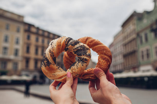 coppia di turisti che tengono bagel obwarzanek tradizionale cucina polacca spuntino sulla piazza del mercato a cracovia. viaggia in europa - piazza delle vettovaglie foto e immagini stock