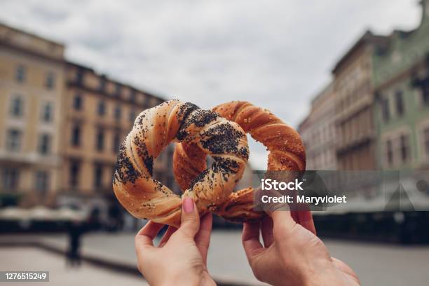Couple Of Tourists Holding Bagels Obwarzanek Traditional Polish Cuisine Snack On Market Square In Krakow Travel Europe Stock Photo - Download Image Now