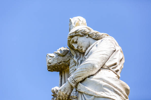 istock Angel, old statue of angle with cross, blue sky background with copy space 1276518510