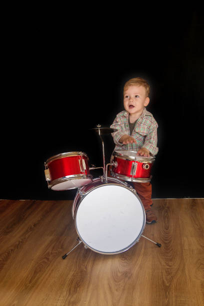 istock Two year caucasian boy is Playing Drum Set Isolated on Black  Background. 1276521825