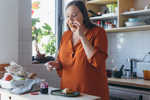 Happy  Plus Size woman having breakfast at home.