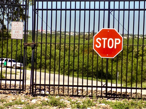 A fence between the United States and Mexico border has a stop sign telling American citizens not to cross even though this is not the technical boundary between the United States and Mexico. The center of the river lies nearly one quarter of a mile beyond the fence.