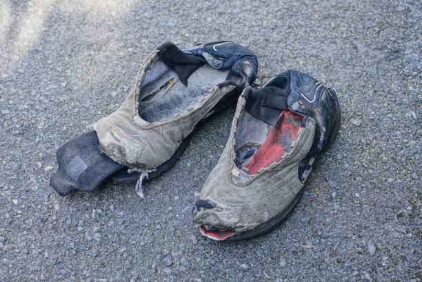 istock two old tattered sneakers stand on gray asphalt 1276523935