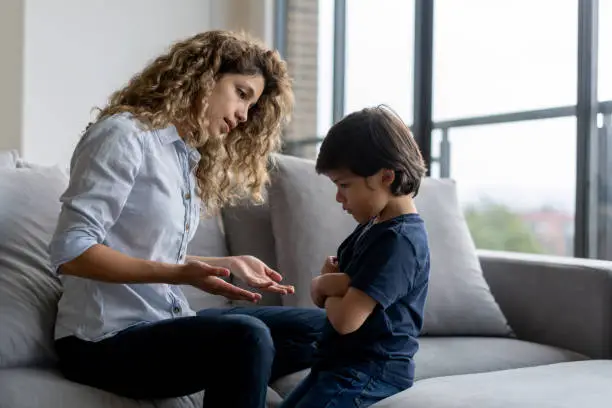 Latin American boy at home having a tantrum at home and mother trying to talk to him - lifestyle concepts