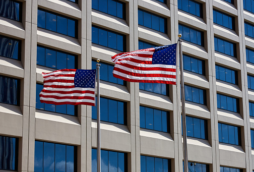 Two American Flags fly in the breeze in front of a building in Lower Manhattan, NYC. These flags are part of the New York Vietnam Veterans Memorial Plaza.