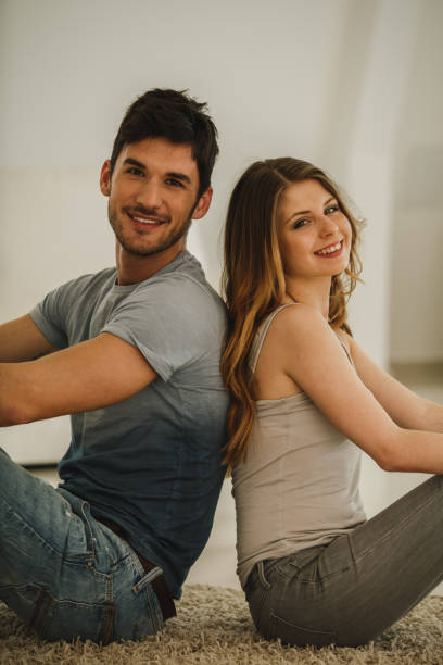 istock Happy couple looking at camera and smiling while sitting back to back 1276532805