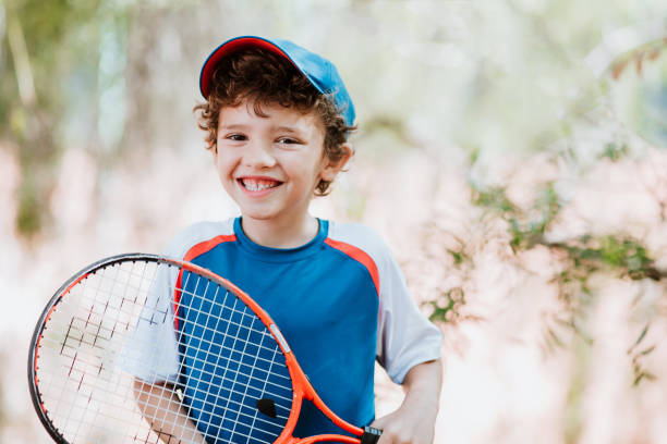 istock Child playing tennis holding a racket and looking at camera smiling 1276533822