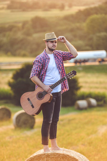 istock Man playing guitar in field 1276541264