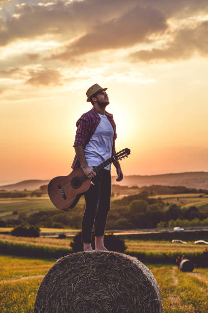 istock Man playing guitar in field 1276541267