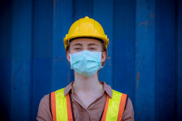 istock Portrait woman dock worker under working and checking production process on dock container warehouse and safety mask face to protect for pollution and virus in factory 1276547535