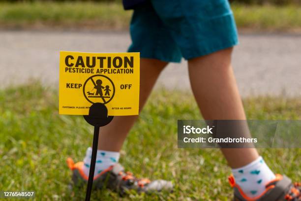 A Yellow Yard Sign Warning Kids And Pets Of The Recent Pesticide Spraying And Advices Them To Stay Away Stock Photo - Download Image Now