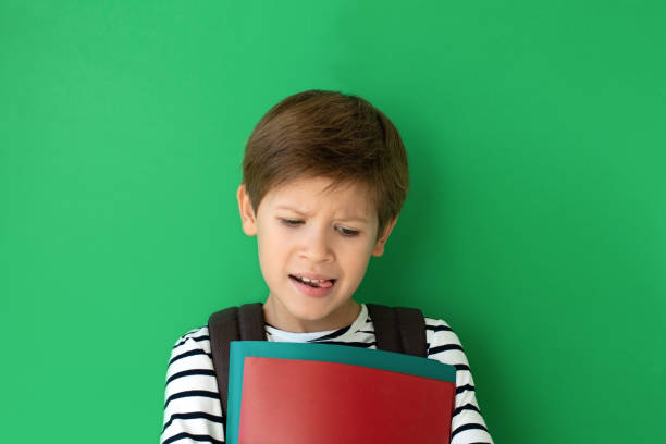 istock Schoolboy with a bored face with copy space. Pupil with a backpack and textbooks. Back to school 1276551373