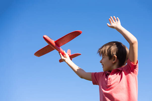 istock boy playing with a red plane against the sky. Happy childrens games 1276551931