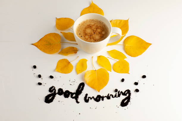 White coffee mug concept: fall yellow with good morning written with coffee ground beans over a white background