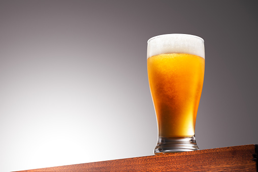 Close up photo of a Glass of beer on a Wooden Surface and Gradient Background With Clipping Path