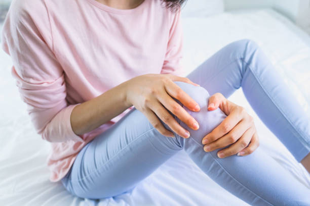 mujer sosteniendo la rodilla con dolor en la cama, cuidado de la salud y concepto médico - sport massaging accident adult fotografías e imágenes de stock