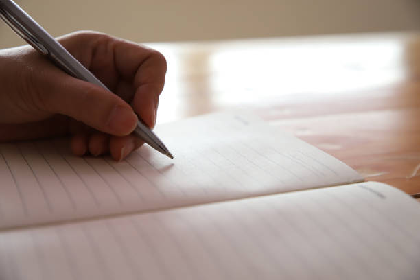 istock Woman hand with pen writing on notebook. 1276561652