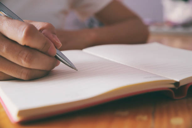 istock Woman hand with pen writing on notebook. 1276561689