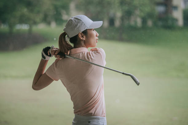 azjatycka chińska młoda golfistka huśtawka jej kierowca na polu golfowym w deszczu - golf women female concentration zdjęcia i obrazy z banku zdjęć