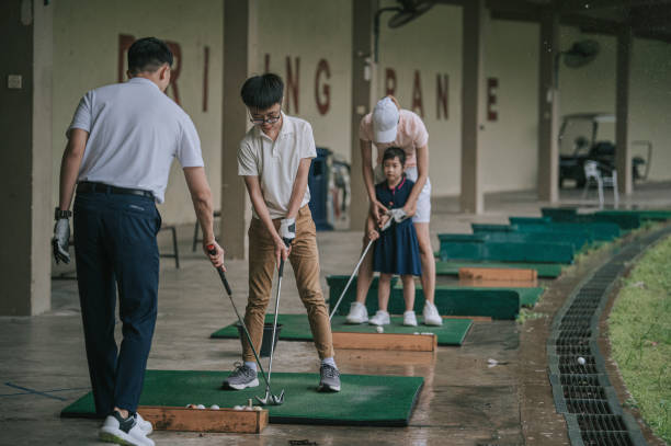 golfeur chinois asiatique de jeune couple enseignant leurs enfants jouant au golf au secteur de conduite de golf - freedom tire swing tire swing photos et images de collection