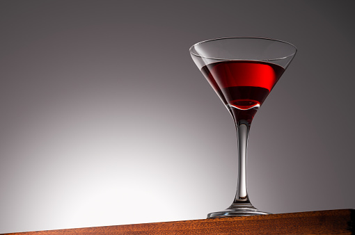 Red Drink in Martini Glass on a Wooden Surface With Gradient Background With Clipping Path