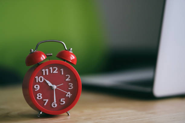 istock Red Alarm Clock and laptop on the wood table 1276564110