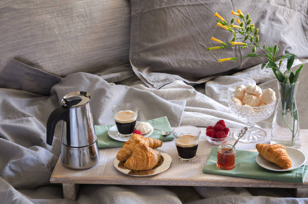 istock Romantic Breakfast  for two in bed. Coffee maker  and coffee glasses, croissants, jam, raspberry meringue and flowers on wood tray. Romantic good morning scenery 1276566428