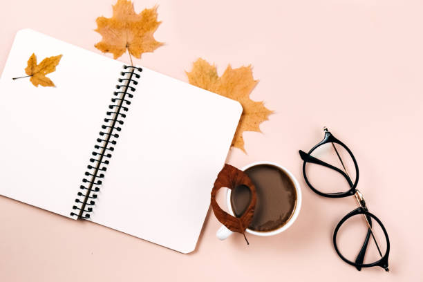 istock Autumn flat lay with dry leaves, notebook, eyeglasses and coffee cup on pastel beige studio background with copy space for advertisement. Thanksgiving, fall, halloween concept. Creative composition 1276566480