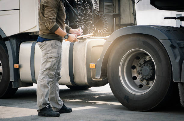 um motorista de caminhão segurando a prancheta verificando a segurança de uma roda de caminhão e pneus. inspeção e segurança. - flatbed truck truck truck driver heavy - fotografias e filmes do acervo