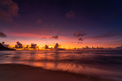 colorful sky over tropical island beach after sunset with reflections on sand beach, long exposure
