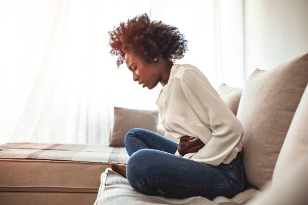 istock Young woman suffering from abdominal pain while sitting on sofa at home 1276568774