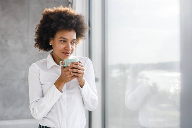 istock Smiling black woman looking through window during home isolation. 1276569706