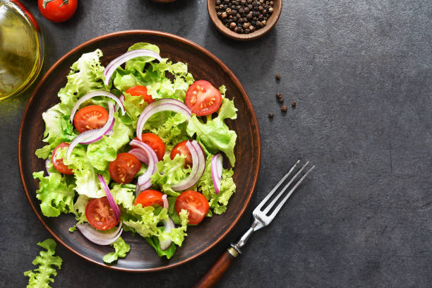 istock Vegetable salad with tomatoes, red onions and sauce on a black background. 1276570607