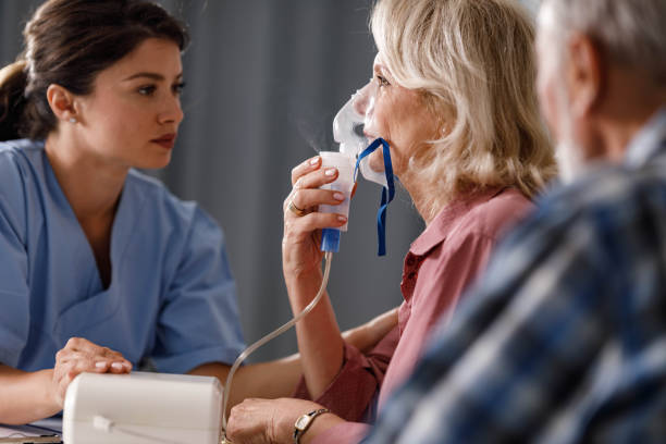 Inhaling through nebulizer at doctor's office! Senior woman using breath vapor while having a medical exam at doctor's office. medical oxygen stock pictures, royalty-free photos & images