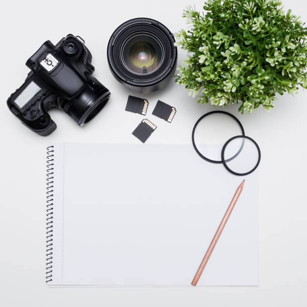 istock photographer's workplace - camera, photography equipment and notepad with pen over white table 1276573993