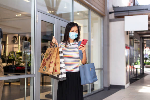 istock Woman wearing face mask using phone in a shopping mall 1276574079