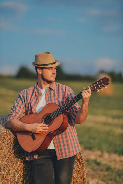 istock Man playing guitar in field 1276574147
