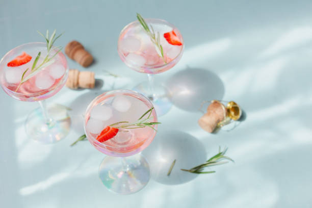 istock Summer drink with white sparkling wine. Homemade refreshing fruit cocktail or punch with champagne, strawberries, ice cubes and rosemary on light blue background. 1276575071