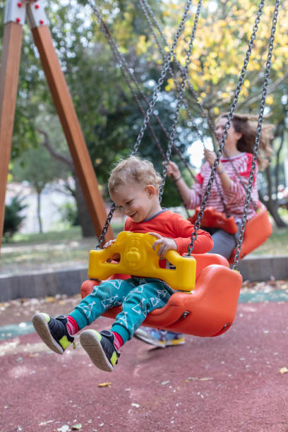 istock Mother with Child Having Fun Swinging at Playground 1276575167