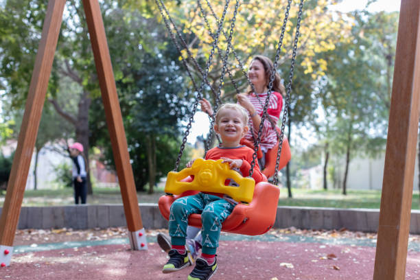istock Mother with Child Having Fun Swinging at Playground 1276575267