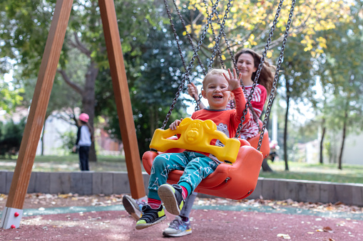 Mother with Child Having Fun Swinging at Playground