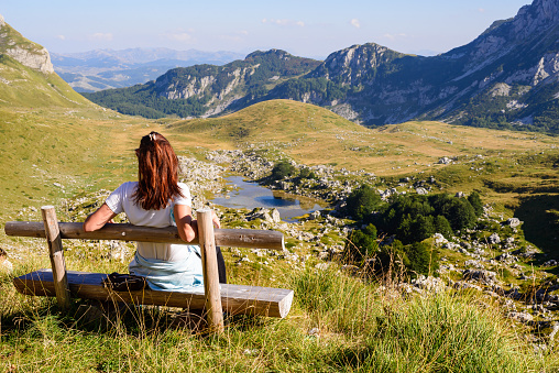 Woman hiker relaxing on bench on Durmitor mountain in Montenegro