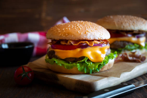 istock Burger with cheese, bacon, tomato and lettuce on dark wooden background 1276579083