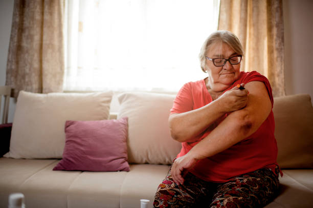 mujer mayor inyectando insulina en el brazo de la suya - insulin fotografías e imágenes de stock