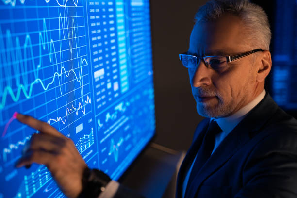 istock The old businessman working on the big blue screen with graphics 1276584544