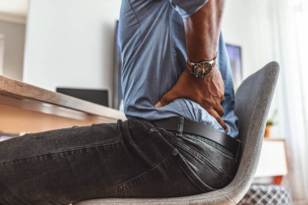 Feeling the strain of a long day at his desk Businessman working sitting at desk feels unhealthy suffers from lower back pain. Damage of intervertebral discs, spinal joints, compression of nerve roots caused by wrong posture and sedentary work. posture stock pictures, royalty-free photos & images