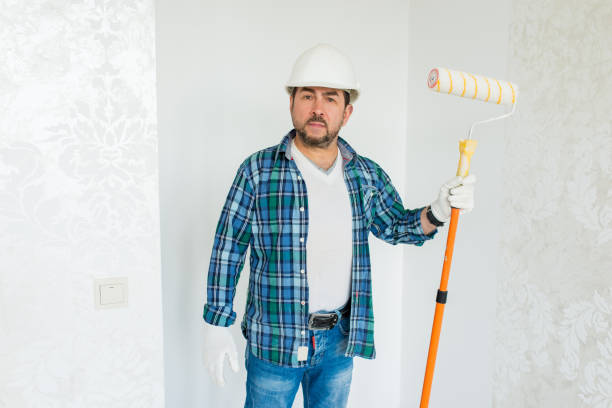 istock Builder repairman in safety helmet with roller 1276586306