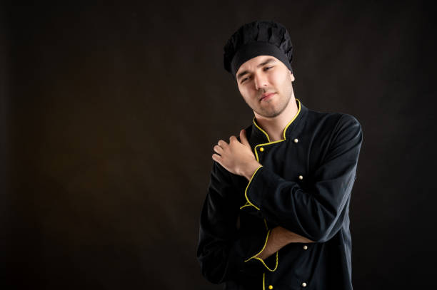 istock Young male dressed in a black chef suit has shoulder pain 1276587013